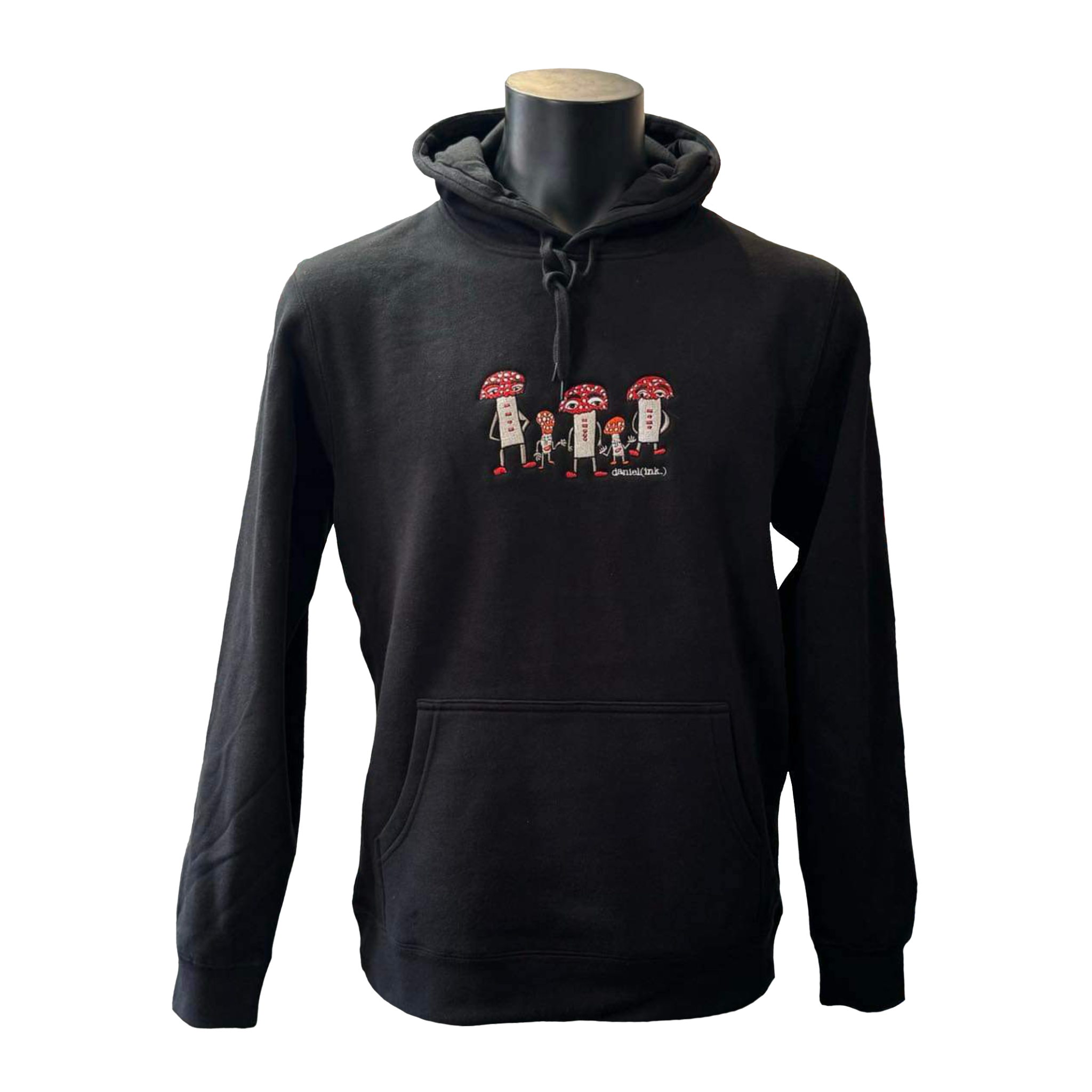Unisex black hoodie featuring an embroidered image of five humanoid mushroom figures, three large and two small, standing next to each other. Each mushroom figure has a red mushroom cap, red shoes, and red accents. The three large mushrooms also have red buttons on their chests which spell "magic" in Morse code. The name daniel(ink.) is embroidered in silver thread underneath the mushroom people.